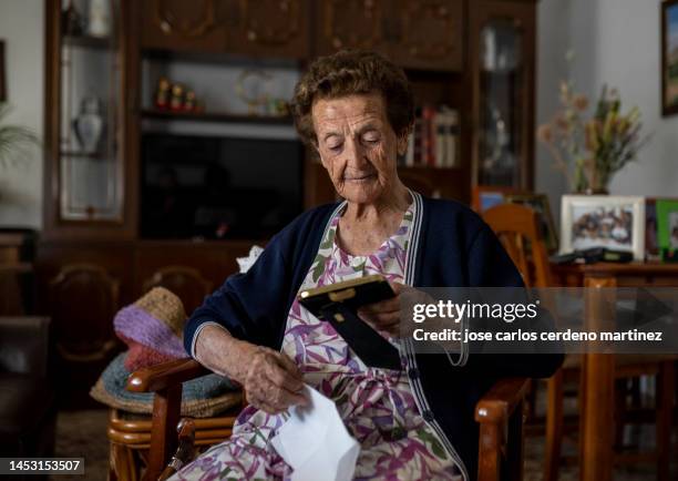 the nostalgic elderly woman sat with the photo frame in her hands, lost in thought as she remembered days gone by. - the lost photographs of captain scott stockfoto's en -beelden