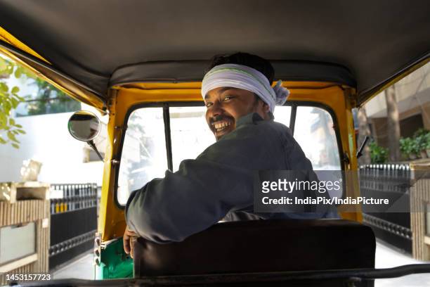 portrait of a happy auto rickshaw driver looking back - tuk tuk stock-fotos und bilder