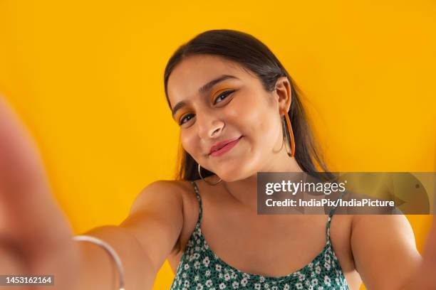 closeup portrait of a teenage girl with arms outstretched towards camera against yellow background - face arms stock pictures, royalty-free photos & images