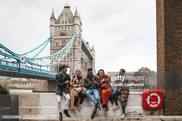 grupo de amigos de vacaciones enviando mensajes de texto en el móvil - london tower bridge fotografías e imágenes de stock