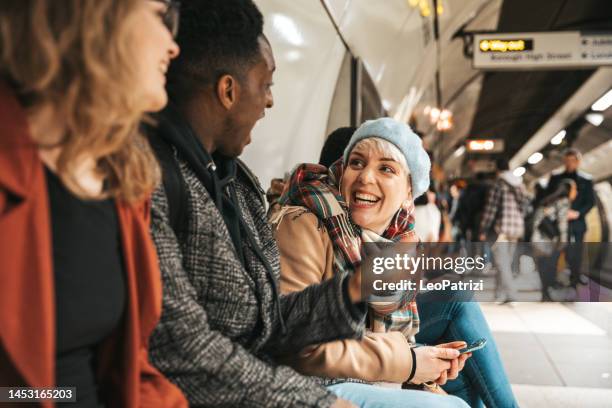 gruppe von multiethnischen freunden, die mit der u-bahn unterwegs sind - london tube stock-fotos und bilder