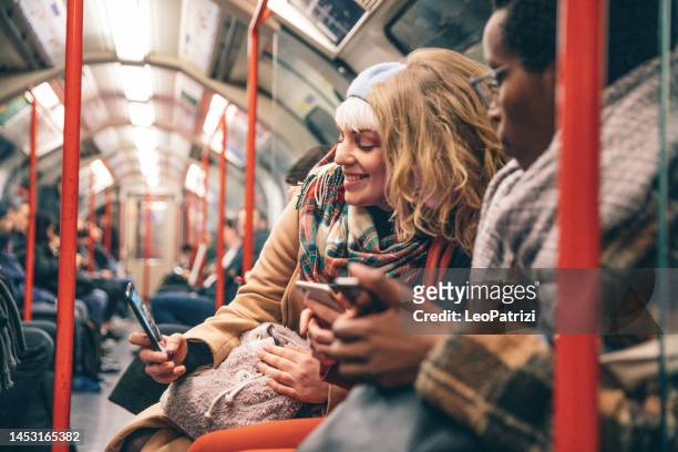 group of friends commuting by subway in london, uk - person on phone stock pictures, royalty-free photos & images