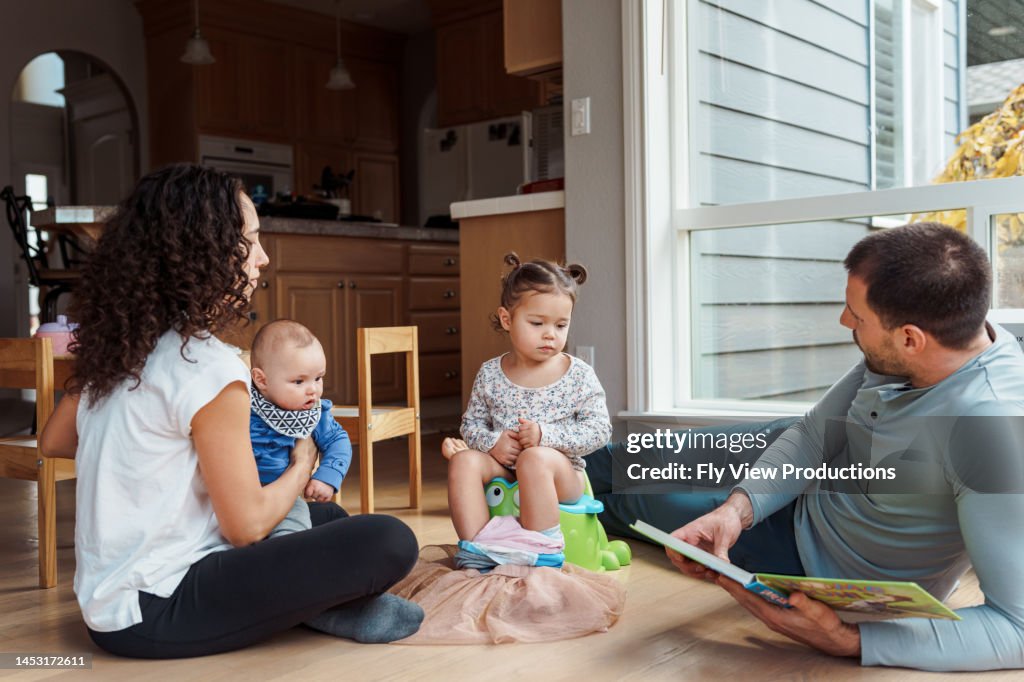 Supportive parents helping toddler daughter learn to use the potty