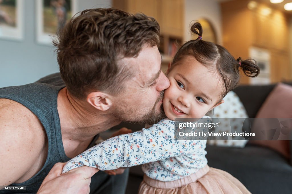 Loving dad kissing toddler daughter on the cheek