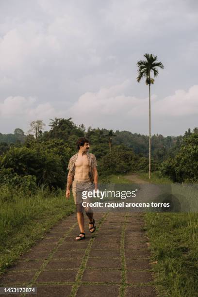 adult man strolling along campuhan ridge walk with his shirt open - ubud rice fields stock pictures, royalty-free photos & images