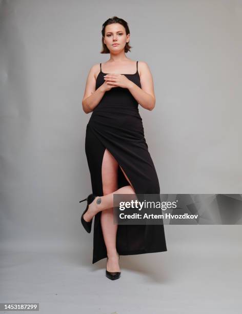 young woman stands in  dress with a slit - form fitted dress stock pictures, royalty-free photos & images