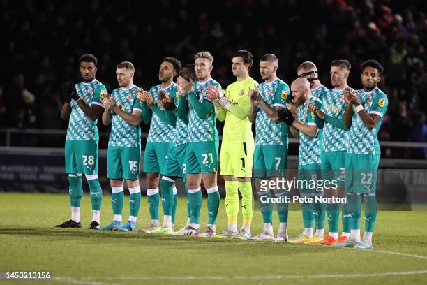 Swindon Town players observe a minutes applause from Fans who have passed away during 2022 prior to the Sky Bet League Two between Northampton Town...