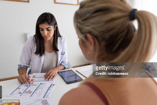 female nutricionist doctor and deportologist in her desk's office during a medical consultation with young woman patient - body mass index chart stock pictures, royalty-free photos & images