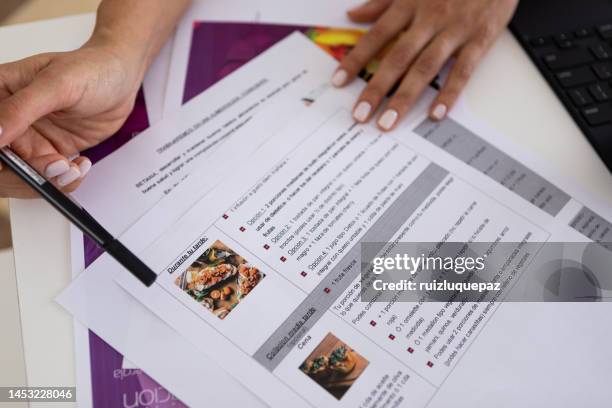 primer plano de las manos de una doctora nutricionista y deportóloga en el consultorio de su escritorio durante una consulta médica señalando un plan de dieta - meal plan fotografías e imágenes de stock