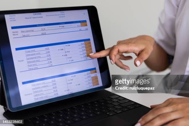close up of hands of a female nutricionist doctor and deportologist  pointing out  a document in her computer during a medical consultation - body mass index chart stock pictures, royalty-free photos & images