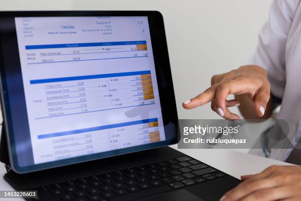 close up of hands of a female nutricionist doctor and deportologist  pointing out  a document in her computer during a medical consultation - body mass index chart stock pictures, royalty-free photos & images