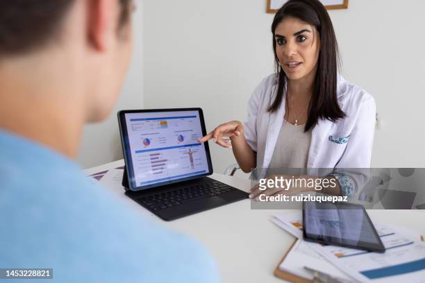 female nutricionist doctor and deportologist in her desk's office during a medical consultation with teenager boy patient - body mass index chart stock pictures, royalty-free photos & images