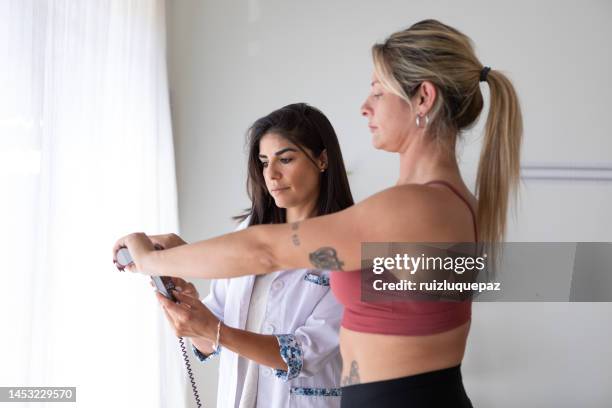 female nutritionist and deportologist weighing female patient on biometric scale during medical consultation - index finger stock pictures, royalty-free photos & images