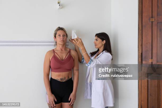 female nutritionist and deportologist mesuring height on a female patient with anthropometric instruments during medical consultation - body mass index chart stock pictures, royalty-free photos & images