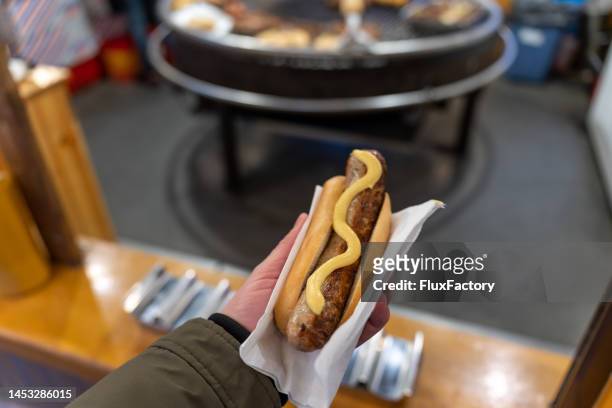 unrecognizable man holding bun with sausage, at the christmas market - stralsund stock pictures, royalty-free photos & images