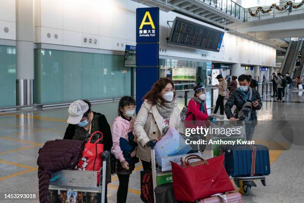 Travellers walk with their luggage at the arrival hall of the Hong Kong International Airport on December 30, 2022 in Hong Kong, China. Authorities...