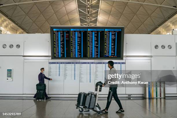 Travellers walk with their luggage at the departure hall of the Hong Kong International Airport on December 30, 2022 in Hong Kong, China. Authorities...