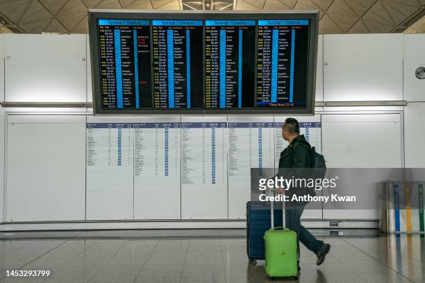Travellers walk with their luggage at the departure hall of the Hong Kong International Airport on December 30, 2022 in Hong Kong, China. Authorities...