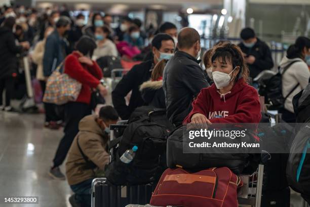 Travellers wait in line to check in at the departure hall of the Hong Kong International Airport on December 30, 2022 in Hong Kong, China....