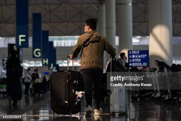 Travellers walk with their luggage at the departure hall of the Hong Kong International Airport on December 30, 2022 in Hong Kong, China. Authorities...
