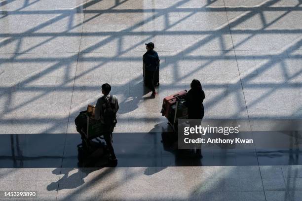 Travellers walk with their luggage at the arrival hall of the Hong Kong International Airport on December 30, 2022 in Hong Kong, China. Authorities...