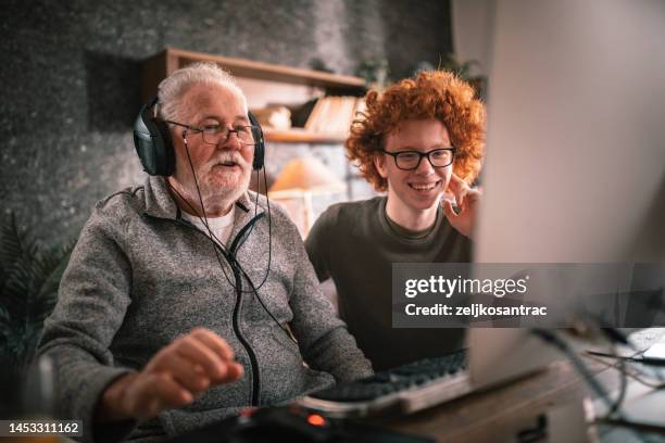 grandfather and grandson sitting around table at home and using computer - showing laptop stock pictures, royalty-free photos & images