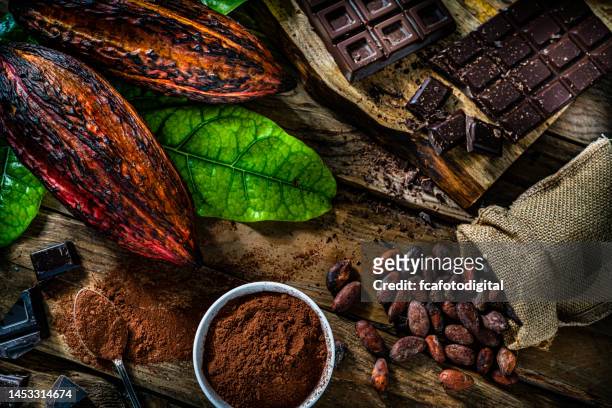 dark chocolate bars, cocoa pods and cocoa powder on rustic wooden table. - bolster stockfoto's en -beelden