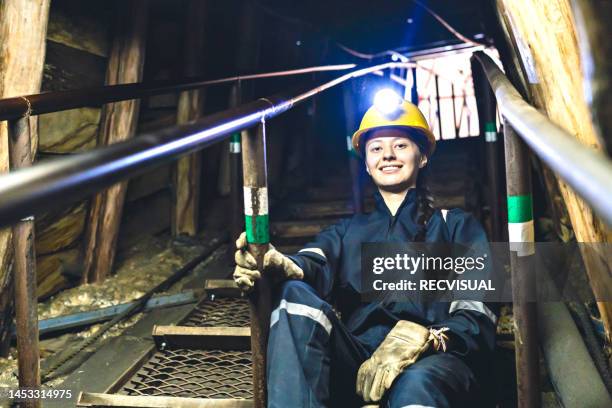 portrait of a miner looking at the camera smiling as she walks down the stairs of a coal mine. - mijnwerker stockfoto's en -beelden