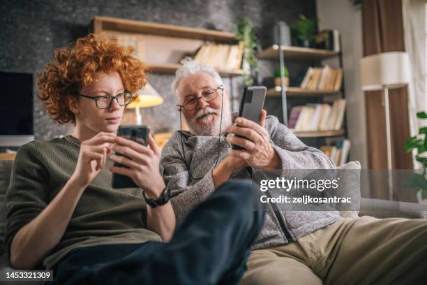 grandfather and grandson having fun and looking a smart phone - adult interior home stock pictures, royalty-free photos & images