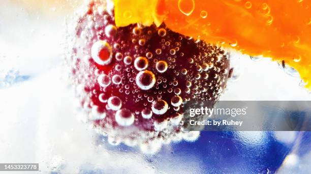 close-up of a refreshing drink with orange and cherry and bubbles on top of it - cherry on top stock-fotos und bilder