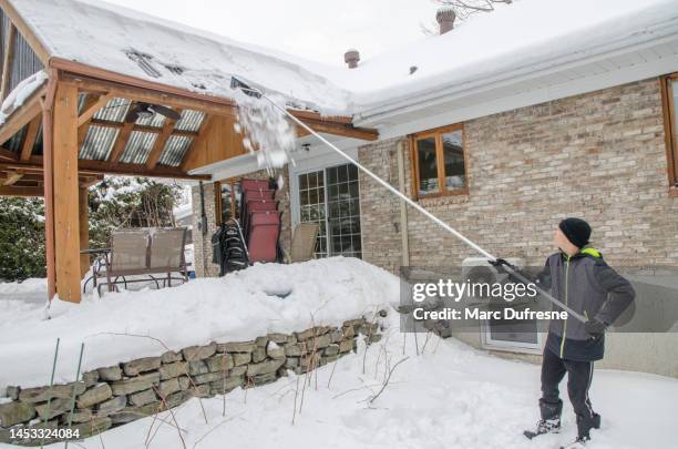 teenage boy removing snow from patio roof - winterdienst stockfoto's en -beelden