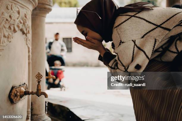 muslimische frau nimmt waschung zum gebet - hands fountain water stock-fotos und bilder