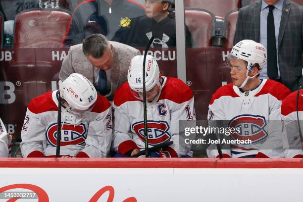 Head coach Martin St. Louis looks at a tablet with Cole Caufield, Jake Evans, and Nick Suzuki of the Montreal Canadiens during a break in action...