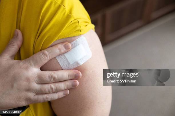 the woman applies one hrt patch to the skin into the outside of upper arm. - band aid stock pictures, royalty-free photos & images