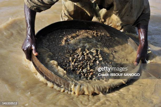 Diamond prospector filters earth from a river on April 28 in Koidu, the capital of the diamond-rich Kono district, in eastern Sierra Leone, some 250...