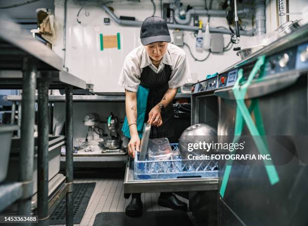 young korean female chef working in restaurant kitchen - dishwasher stockfoto's en -beelden