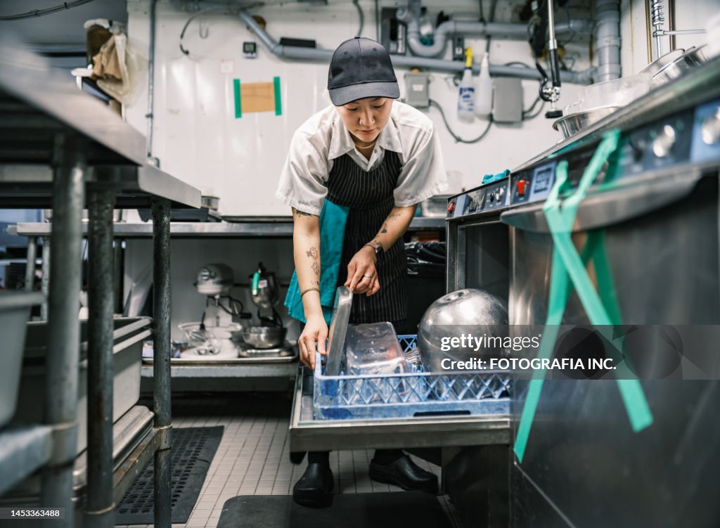 Young Korean female chef working in restaurant kitchen