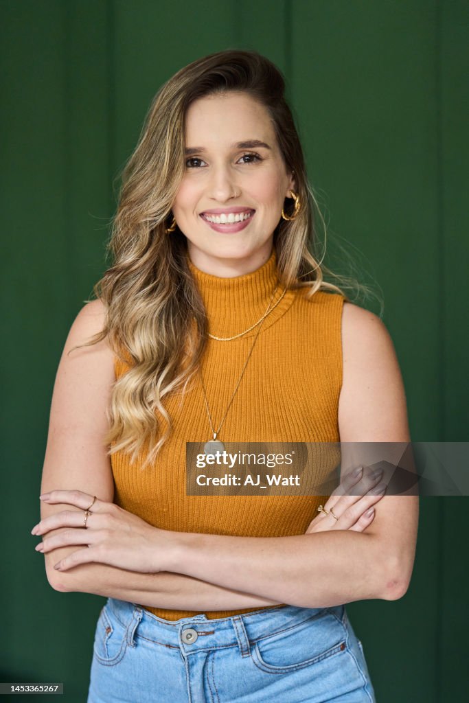 Jovem arquiteta sorrindo enquanto está de pé com os braços cruzados