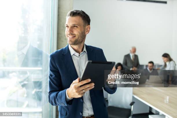 cheerful caucasian young businessman freelancer using digital tablet inside modern office - financial expertise stock pictures, royalty-free photos & images