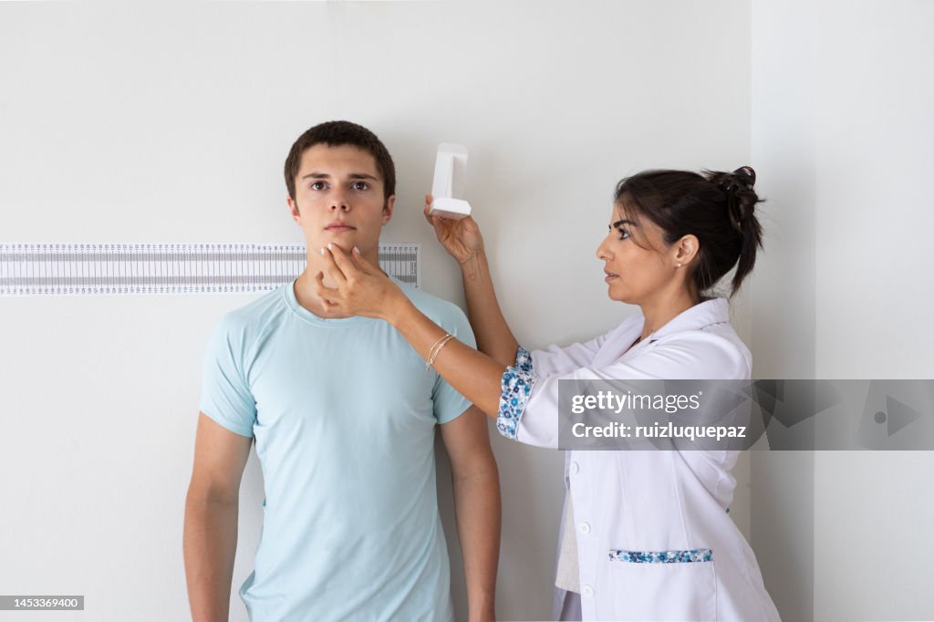 Female nutritionist and deportologist mesuring height of teenager patient during medical consultation