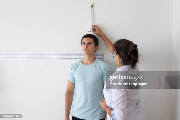 female nutritionist and deportologist mesuring height of teenager patient  during medical consultation - cinema society screening of you will meet a tall dark stranger arrivals stockfoto's en -beelden