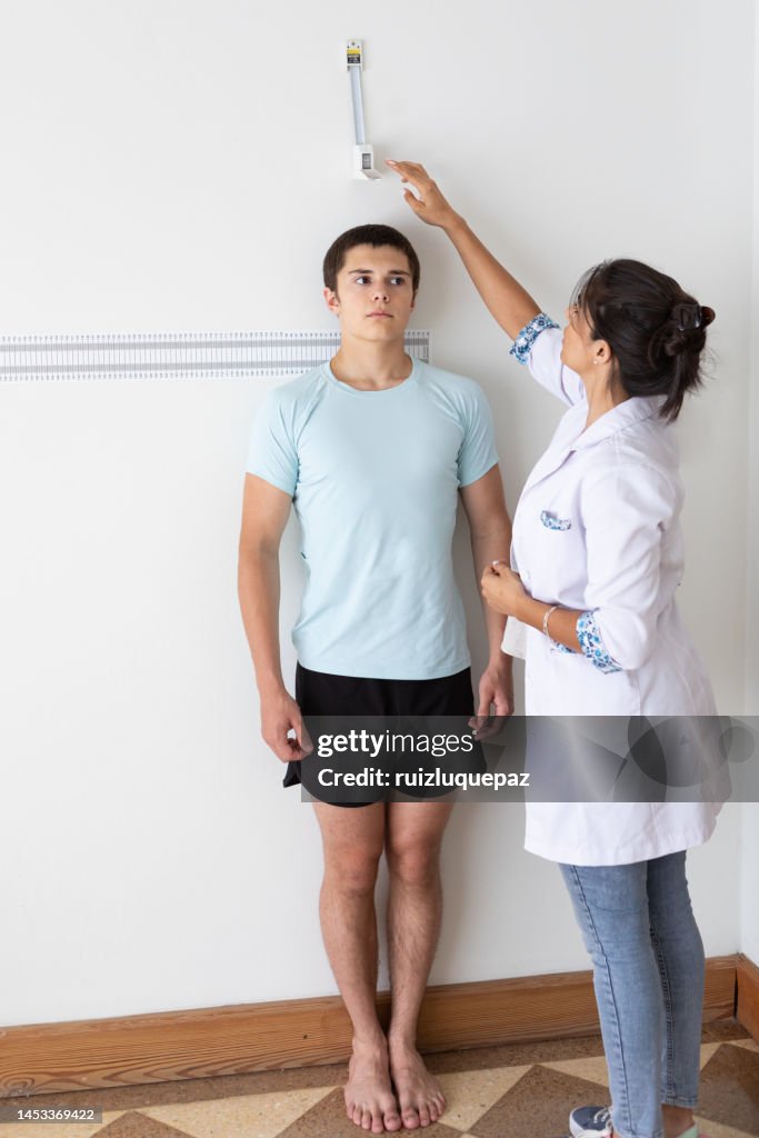 Nutricionista e deportologista do sexo feminino medindo a altura de paciente adolescente durante consulta médica