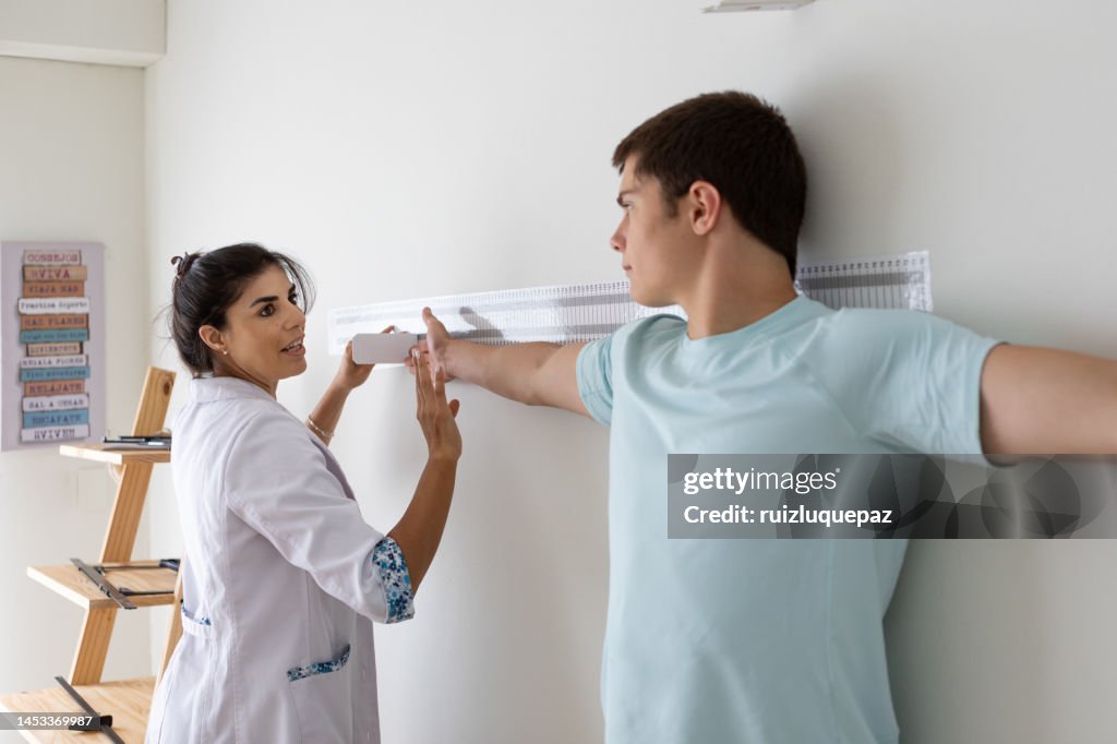 Female nutritionist and deportologist in her office during a medical consultation measuring the arm and torso length of her teenage patient with an anthropometric instrument