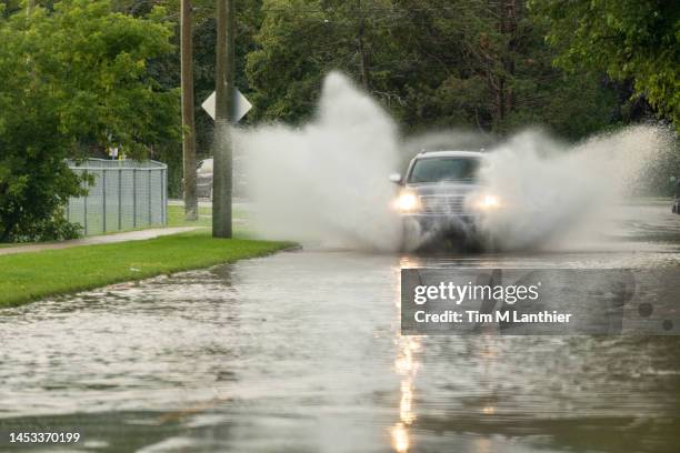 car travelling through flood after extreme rain - pluie diluvienne photos et images de collection
