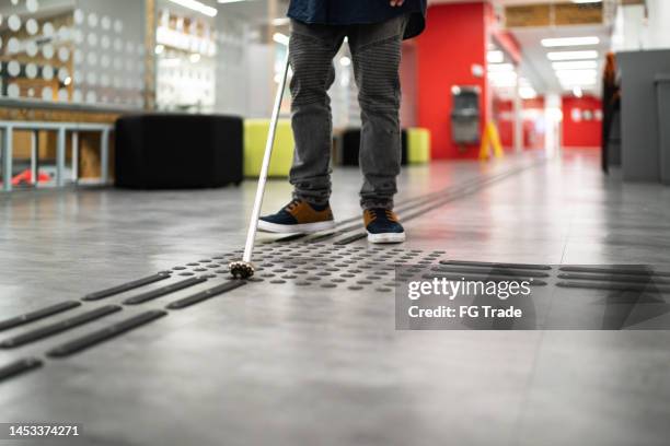 sehbehinderter mann, der an der universität mit einem gehstock spazieren geht - visual impairment stock-fotos und bilder