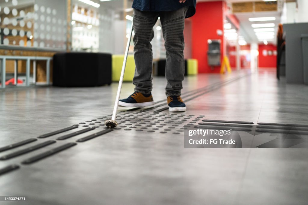 Visually impaired man using walking cane to walk at university