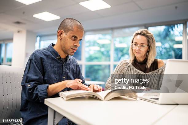mid adult man visually impaired man reading a braille book at university - visually challenged stock pictures, royalty-free photos & images