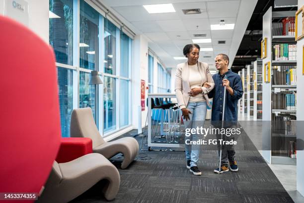 mature teacher accompanying visually impaired at university - disability worker stock pictures, royalty-free photos & images