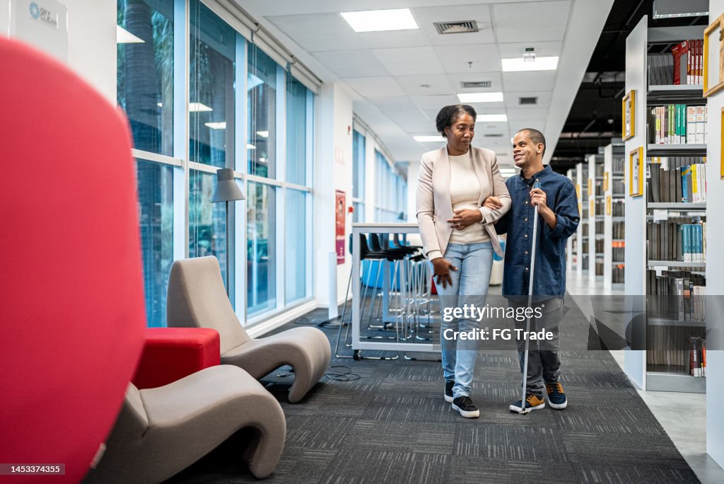 Mature teacher accompanying visually impaired at university