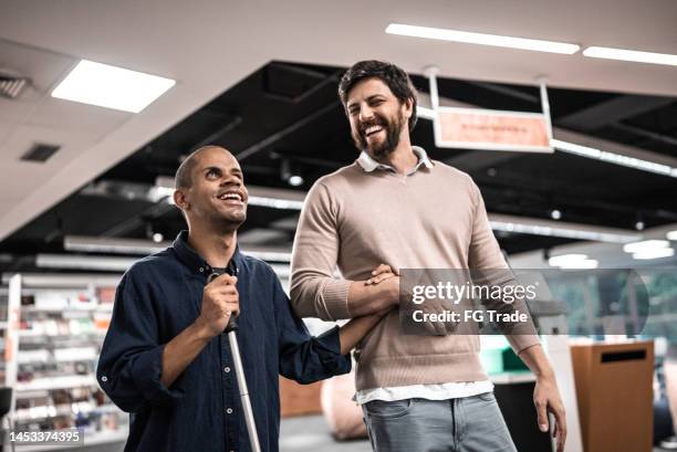 mid adult man visually impaired talking with friend at university - blind person stock pictures, royalty-free photos & images